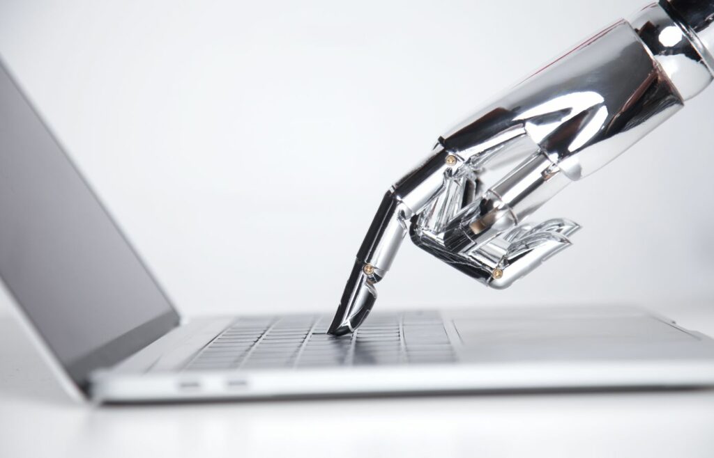 Blog banner showing a robotic hand pressing a laptop keyboard to illustrate the title "Machine Translation vs. human Translation: Will Artificial Intelligence Replace the World’s Second Oldest Profession?"