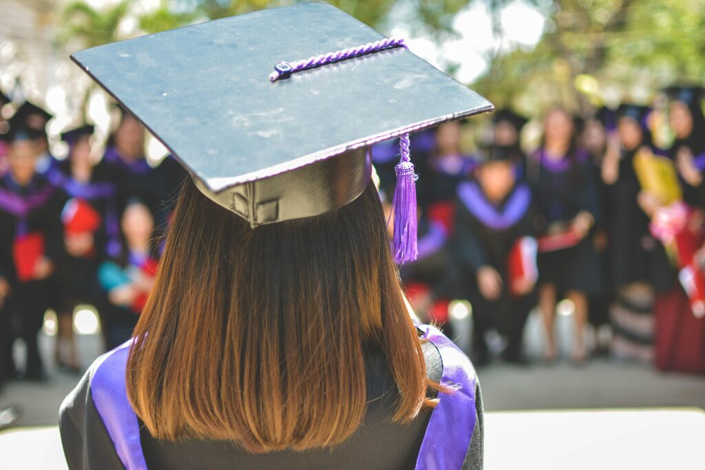 Woman standing in graduation attire facing colleagues.