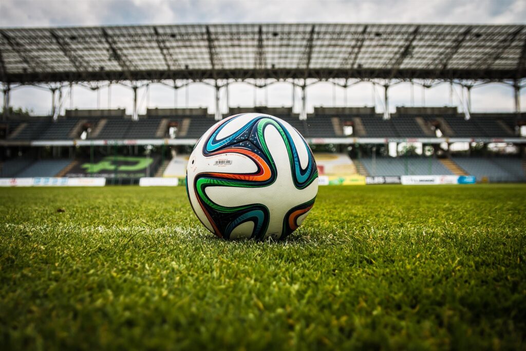 A soccer ball sitting on an empty field within a stadium.