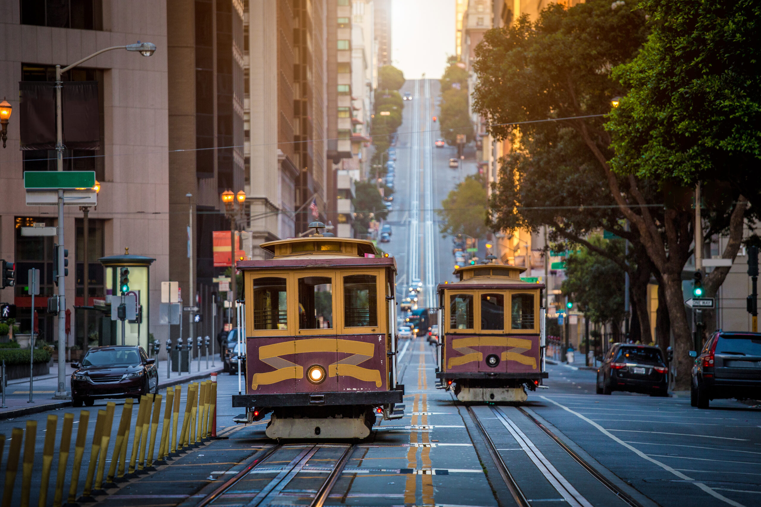 Classic view of historic traditional Cable Cars riding on famous California Street in beautiful early morning light at sunrise in summer, San Francisco, California, USA