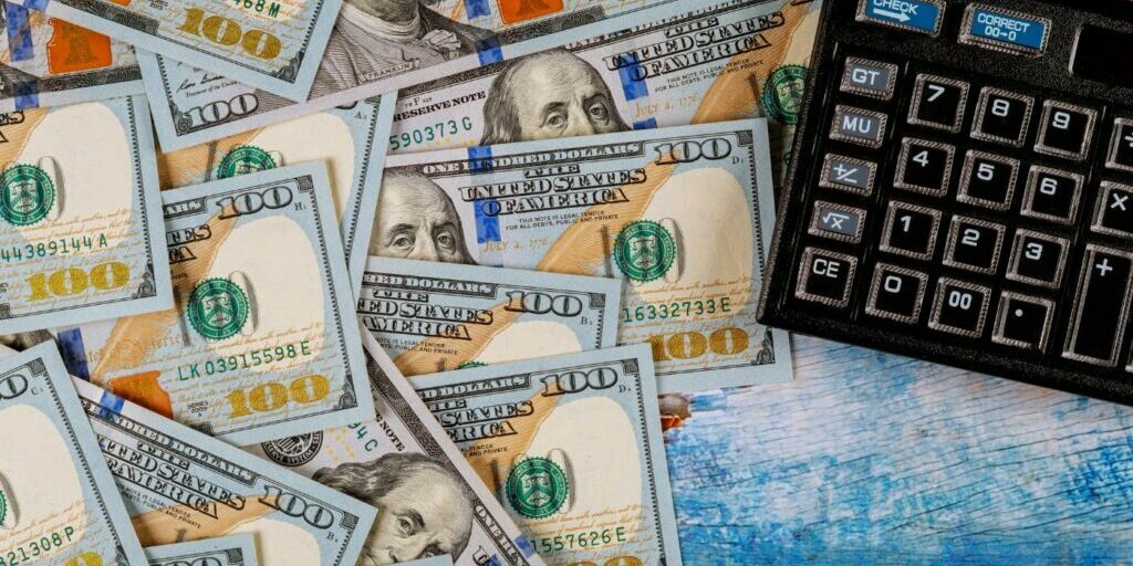 Cost of translation A calculator and several hundred dollar bills symbolizing the cost of translation services