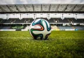 A soccer ball sitting on an empty field within a stadium.